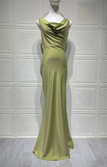 Green evening gown on a mannequin against a white paneled wall.