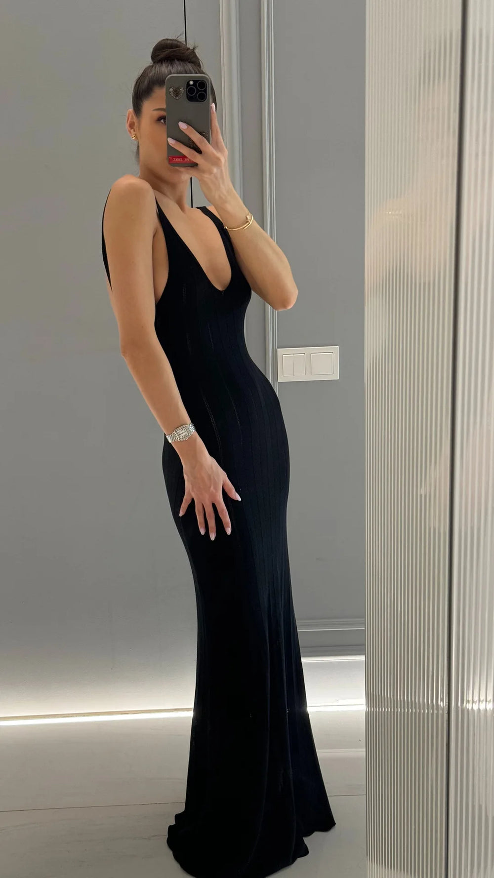 Person wearing a black evening gown in front of a mirror.