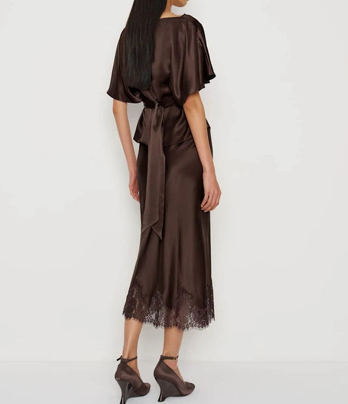 Woman wearing a brown satin dress with lace hem on a white background