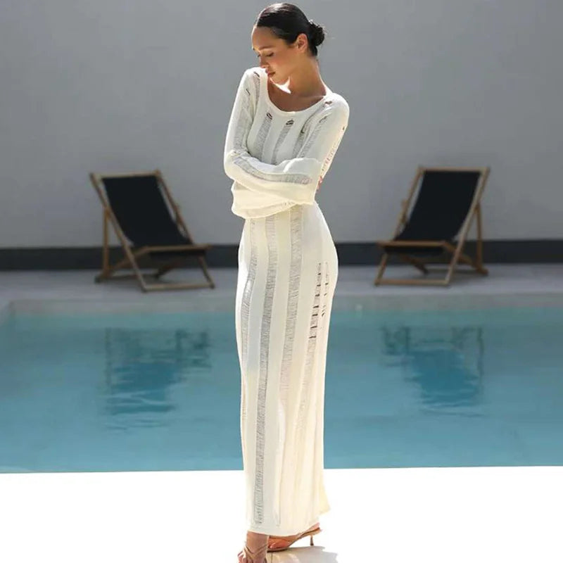 Woman in a white dress standing by a pool with lounge chairs in the background