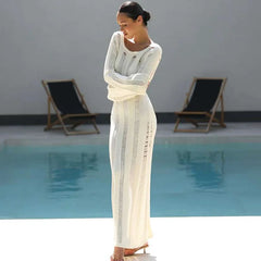 Woman in a white dress standing by a pool with lounge chairs in the background