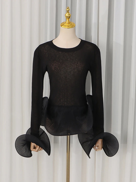 Black sheer knit top with voluminous pleated flare sleeves and ruffled hem