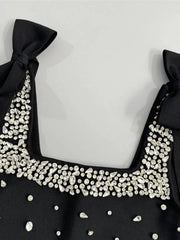 Black top with a decorative neckline featuring small pearls on a light gray background