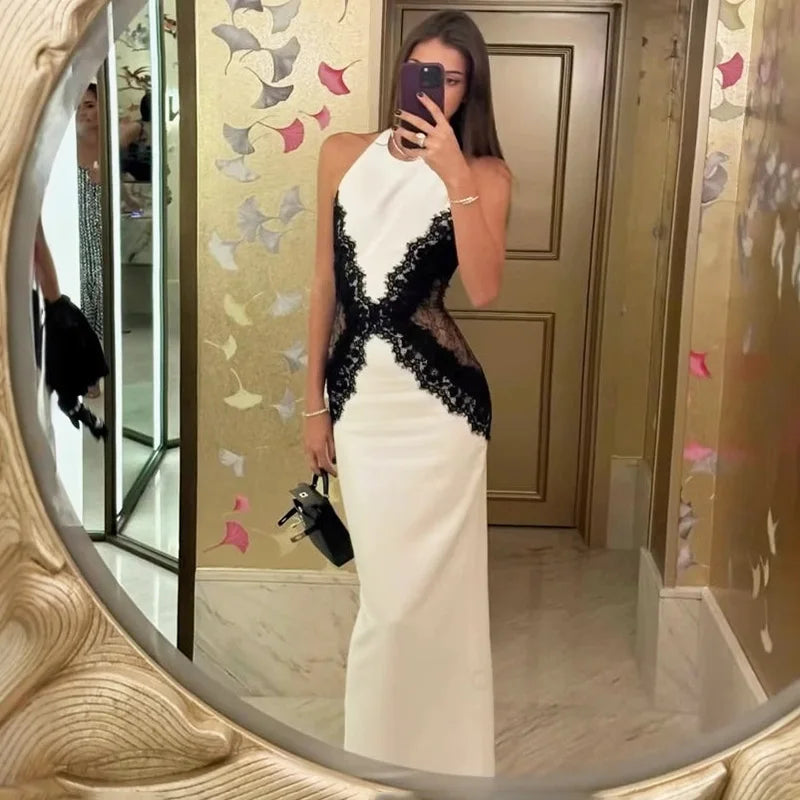 Woman taking a mirror selfie wearing a white and black dress.