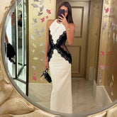 Woman taking a mirror selfie wearing a white and black dress.
