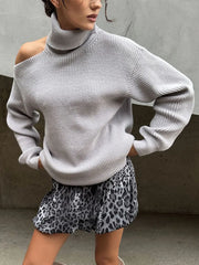 Person wearing a light gray sweater and leopard print skirt against a neutral background