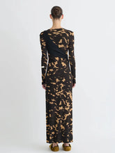 Woman wearing a long black dress with a gold pattern from behind