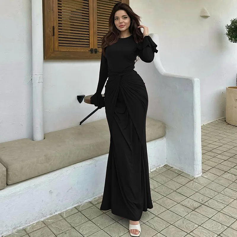 Woman in a black dress standing in a tiled room.