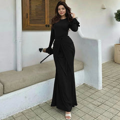 Woman in a black dress standing in a tiled room.