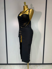 Black dress with gold accents on a mannequin against a plain background