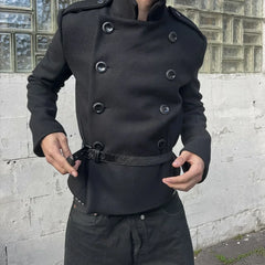 Person wearing a black coat with a textured wall background