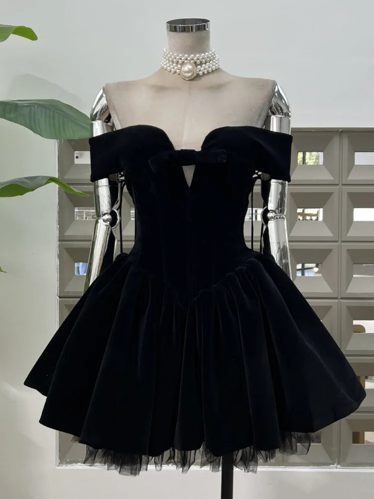 Black off-shoulder dress on a mannequin with a pearl necklace against a light background