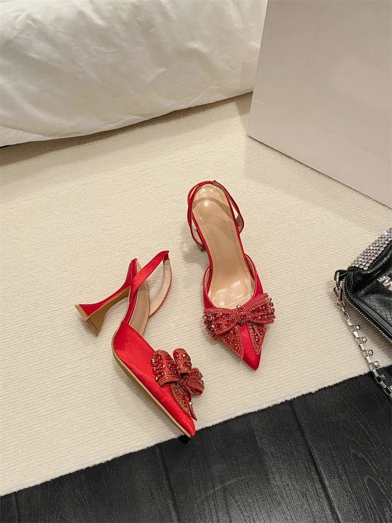 Red high-heeled shoes with bow details on a light surface