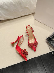 Red high-heeled shoes with bow details on a light surface