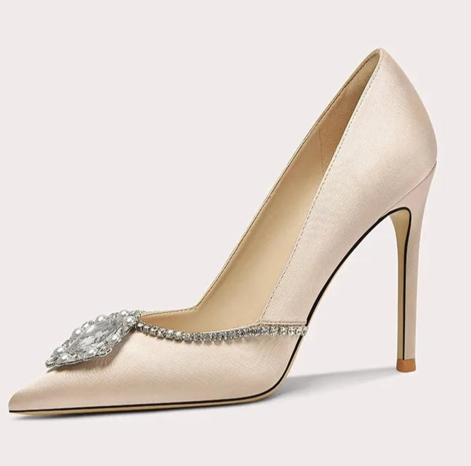Beige high-heeled shoe with decorative element on a light gray background