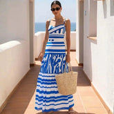 Woman wearing a blue and white striped bandage bodysuit and tiered maxi skirt on a balcony overlooking the ocean.