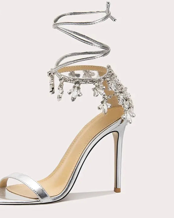 Silver high-heeled sandal with intricate detailing on a white background