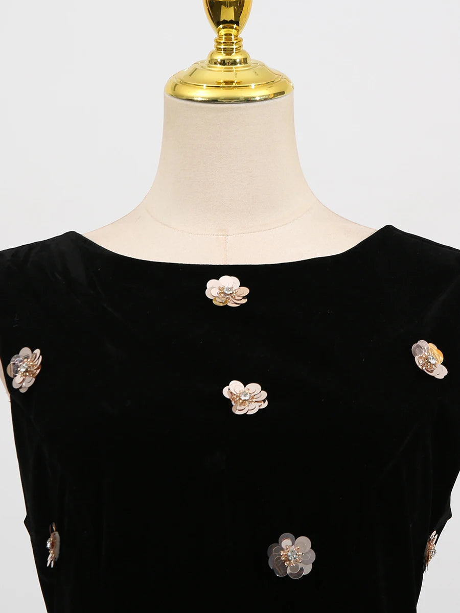 Black dress with floral embellishments on a mannequin against a white background