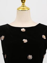 Black dress with floral embellishments on a mannequin against a white background