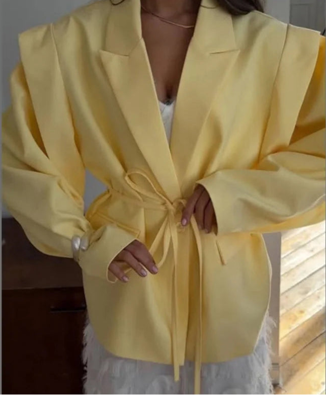 Person wearing a yellow blazer with a plain background