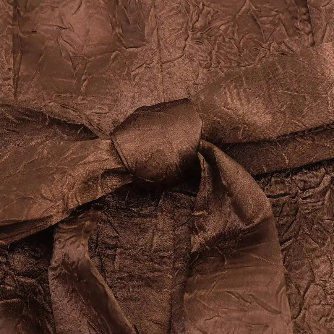 Close-up of crumpled brown fabric with a bow