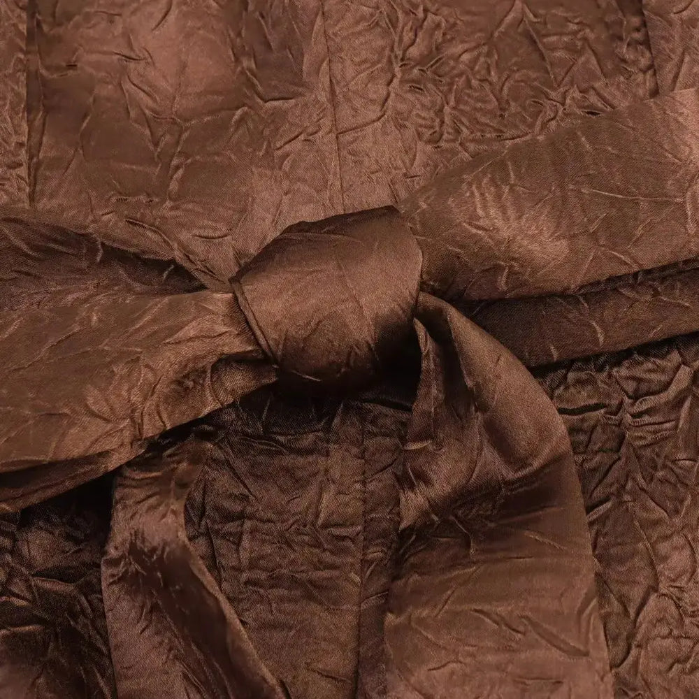 Close-up of crumpled brown fabric with a bow