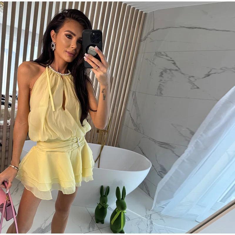 Woman in a yellow dress taking a mirror selfie in a modern interior setting.
