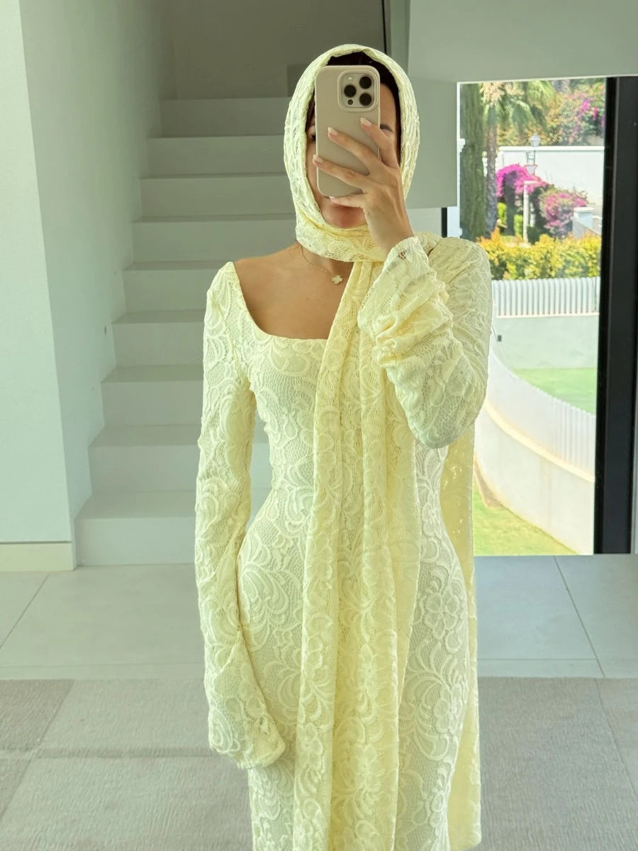 Person wearing a light yellow lace outfit taking a mirror selfie.