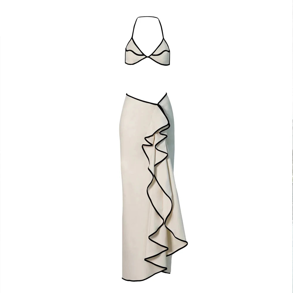 White bikini top and a white ruffled maxi skirt with black contrast trim laid flat.