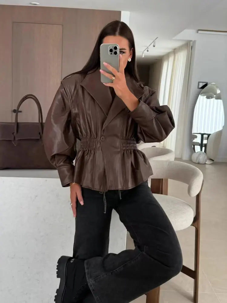 Model wearing a brown faux leather jacket with cinched waist and high neck.