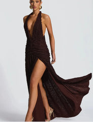 Woman wearing a brown halter neck dress with a slit on a white background