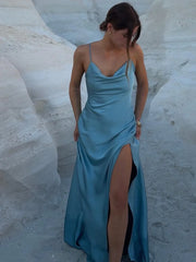 Woman in a blue evening gown with a high slit standing on a textured white surface.