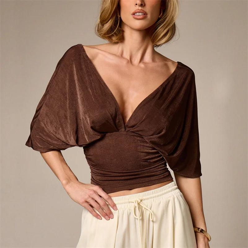 Woman wearing a brown top with puff sleeves and a beige skirt on a neutral background
