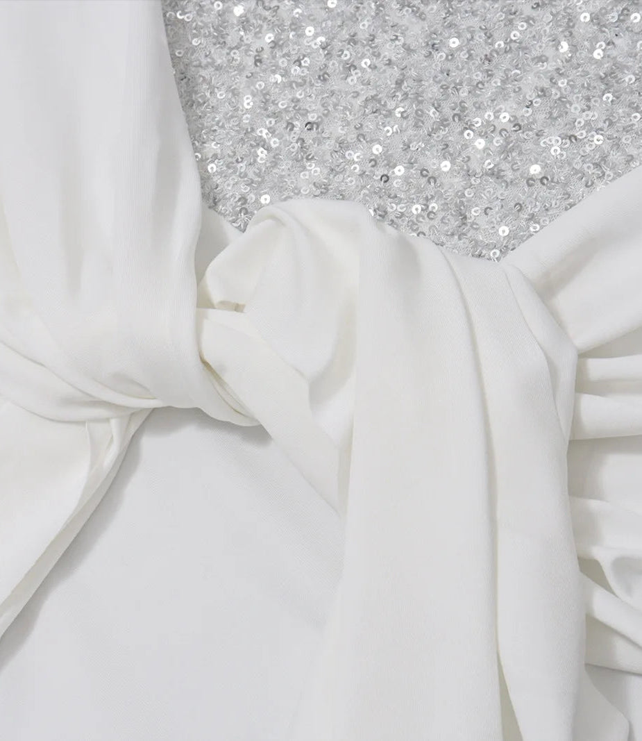 Close-up of white fabric with a textured silver surface underneath