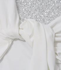 Close-up of white fabric with a textured silver surface underneath