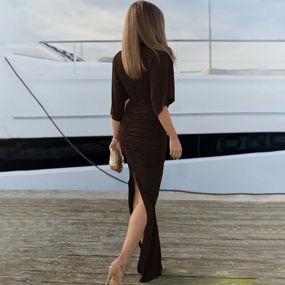 Woman in a brown dress standing on a dock with a yacht in the background