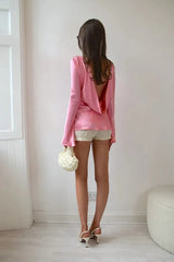 Back view of long sleeve pink open-back satin top indoors