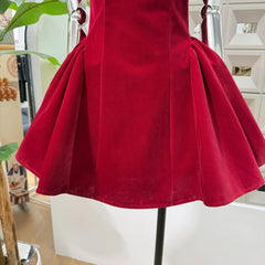 Red dress on a mannequin in an indoor setting with plants and furniture.