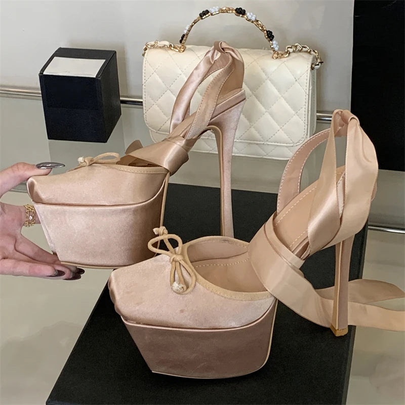 Beige high-heeled shoes with a matching handbag on a reflective surface.
