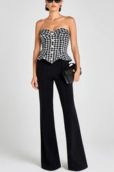 Woman wearing a black and white checkered top with black pants on a white background