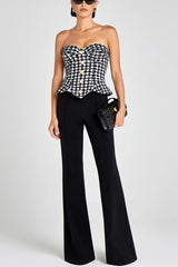 Woman wearing a black and white checkered top with black pants on a white background
