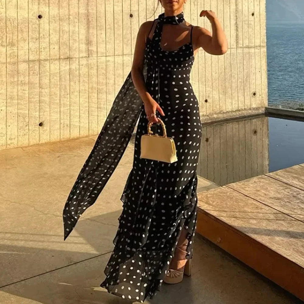 Woman in a black polka dot dress holding a yellow handbag by a waterfront.