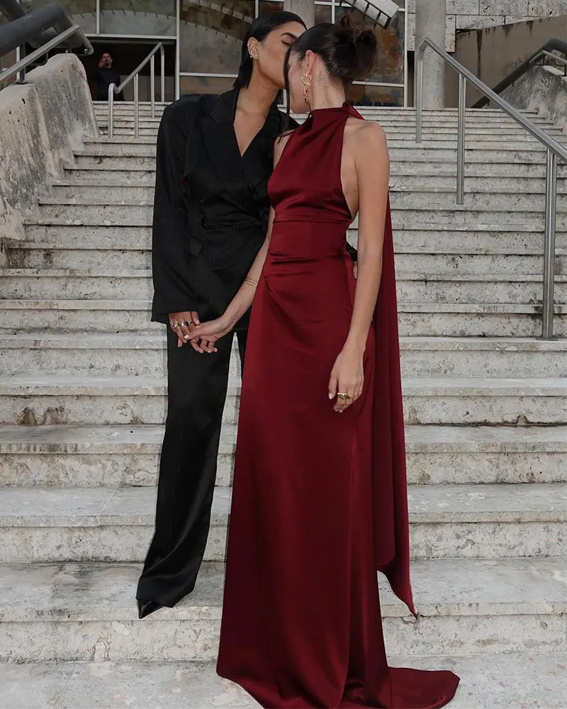 Two people standing on a staircase, one in a black outfit and the other in a red dress.