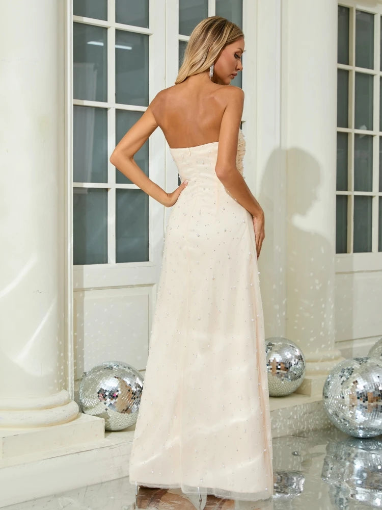 Woman in a strapless white gown standing in a decorated room with disco balls.