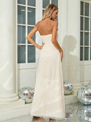 Woman in a strapless white gown standing in a decorated room with disco balls.