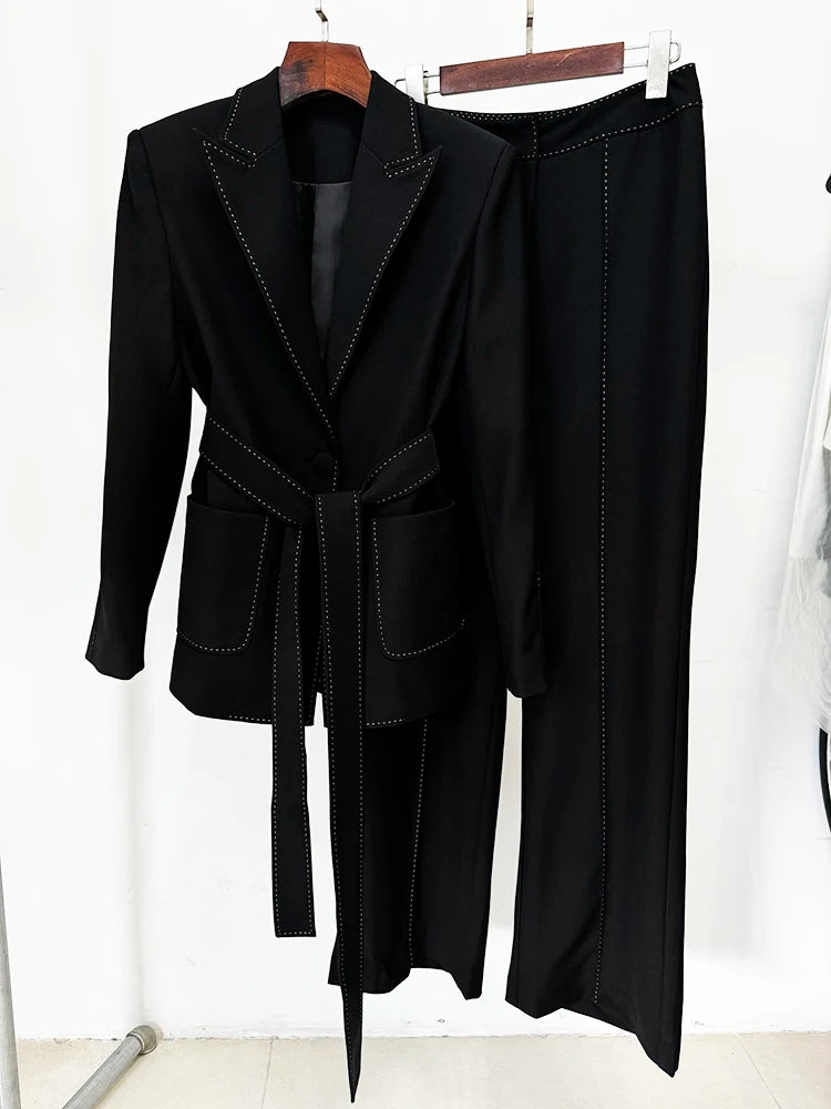 Black belted blazer and wide-leg pants suit with contrast stitching, displayed on a hanger, showing the front.