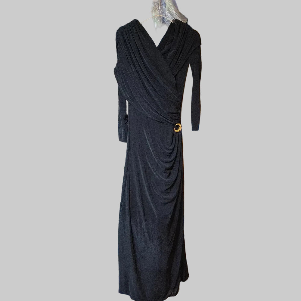 Black draped dress with a gold button on a gray background