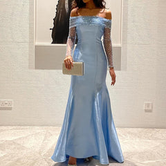 Woman wearing a light blue off-shoulder evening gown with a plain background