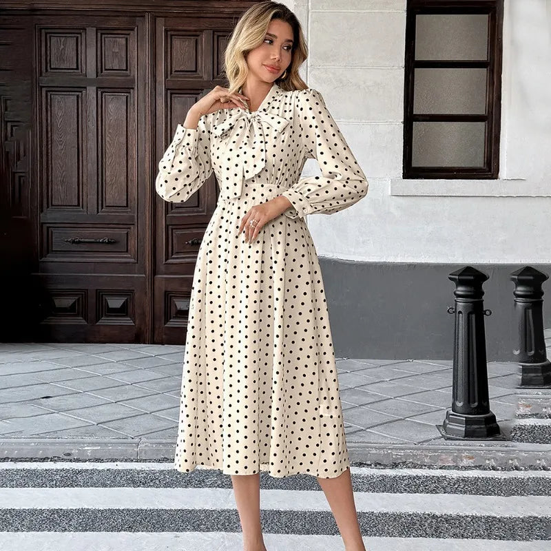 Woman in a polka dot dress standing on a street with a building in the background