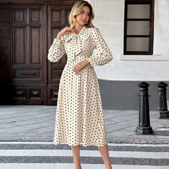 Woman in a polka dot dress standing on a street with a building in the background